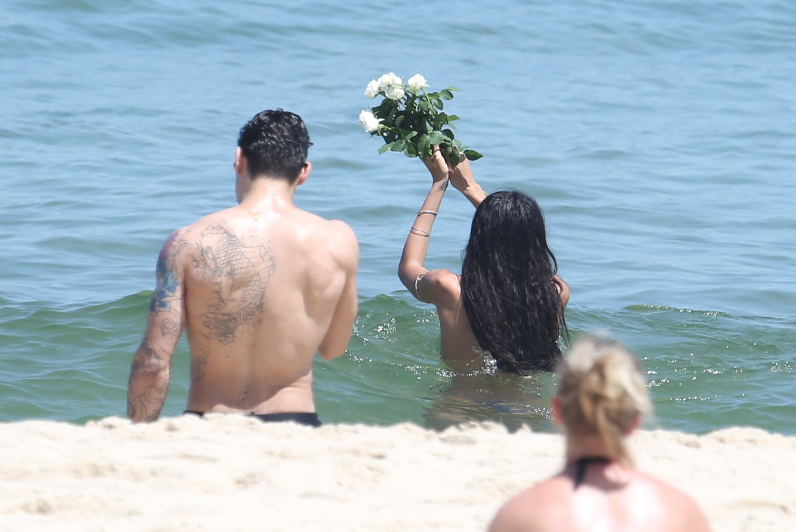 Lea T. vai à praia e oferece flores no mar
