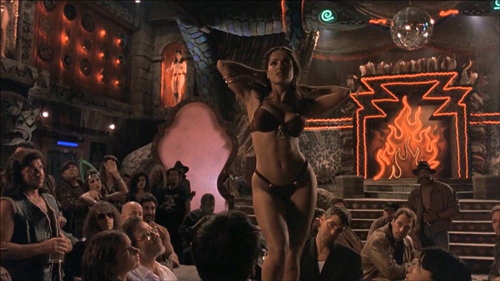 Salma Hayek em “Um Drink Para o Inferno” (1995), dirigido por Robert Rodriguez e escrito por Quentin Tarantino, é uma vampira que dança num bar de prostitutas
