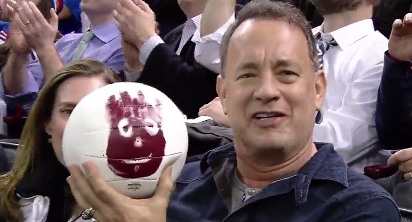 Tom Hanks brinca com o presente que recebeu no jogo do NY Rangers
