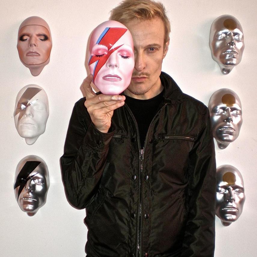 O músico comprou uma coleção de máscaras inspiradas na cara dele mesmo pela bagatela de 250 libras cada uma. As obras são do artista plástico inglês Mark Wardel, que aparece na foto.