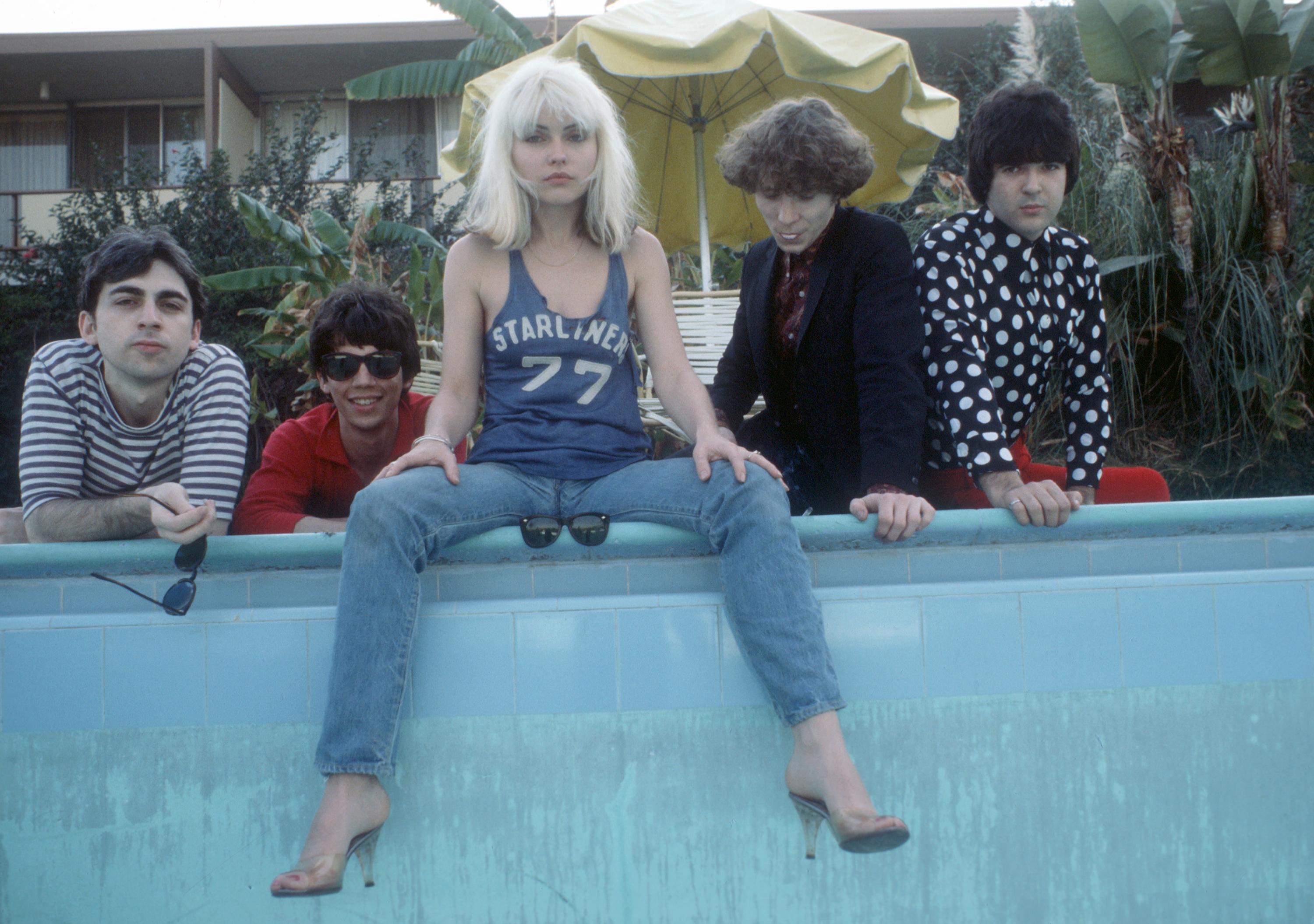 LOS ANGELES - 1977:  Chris Stein (in striped shirt), Jimmy Destri (in gray shirt with sunglasses), Debbie Harry (in Starliner 77 t-shirt), Gary Valentine (in black suit) and Clem Burke (in polka dot shirt) of the rock and roll band "Blondie" pose for a portrait session at the Bel Air Sand Hotel in 1977 in Los Angeles, California. (Photo by Suzan Carson/Michael Ochs Archives/Getty Images)