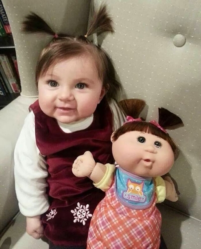 Uma menina no meio de duas bochechas e uma boneca