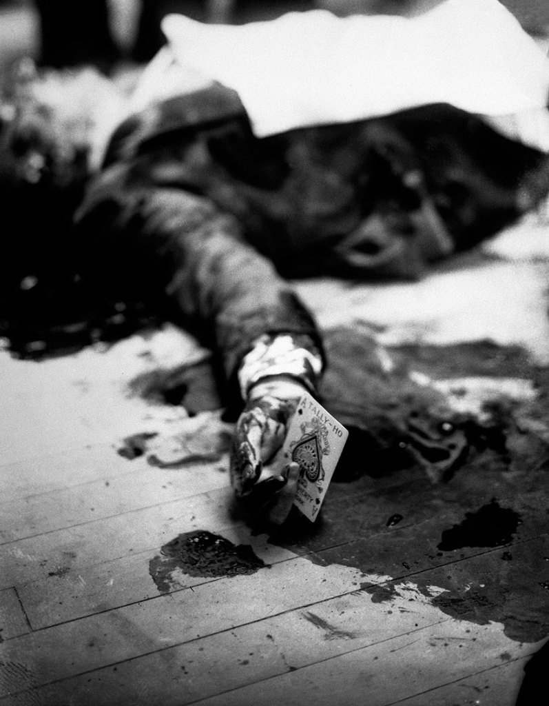O chefe da máfia Joe Masseria morto no chão de um restaurante do Brooklyn, em Nova York, segurando a carta ás de espadas, em 1931