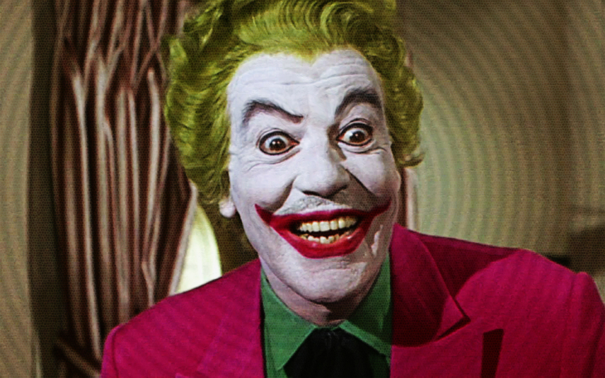 Cesar Romero vive o palhaço do crime na série dos anos 60. Para ser fiel ao tom do personagem da HQ na época, Romero fez um Coringa debochado e caricato. Bem menos sombrio.