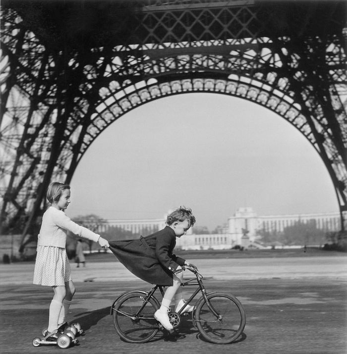 Duas crianças se divertem embaixo da Torre Eiffel