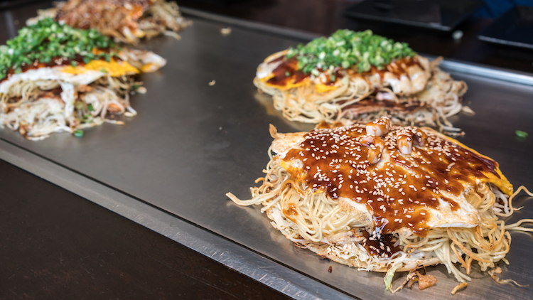  Esta especialidade regional de Hiroshima e Kansai é preparado com uma fina camada de massa coberta com ovos, repolho, carne (geralmente barriga de porco), lulas, macarrão e queijo coberto com molho especial.
