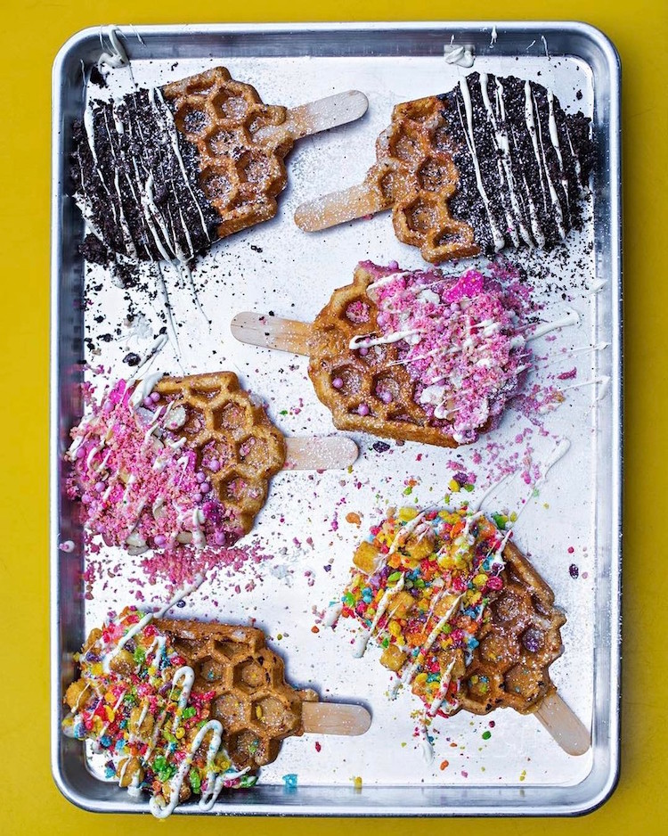 Com coberturas coloridas, waffle no palito desponta como nova sobremesa na moda
