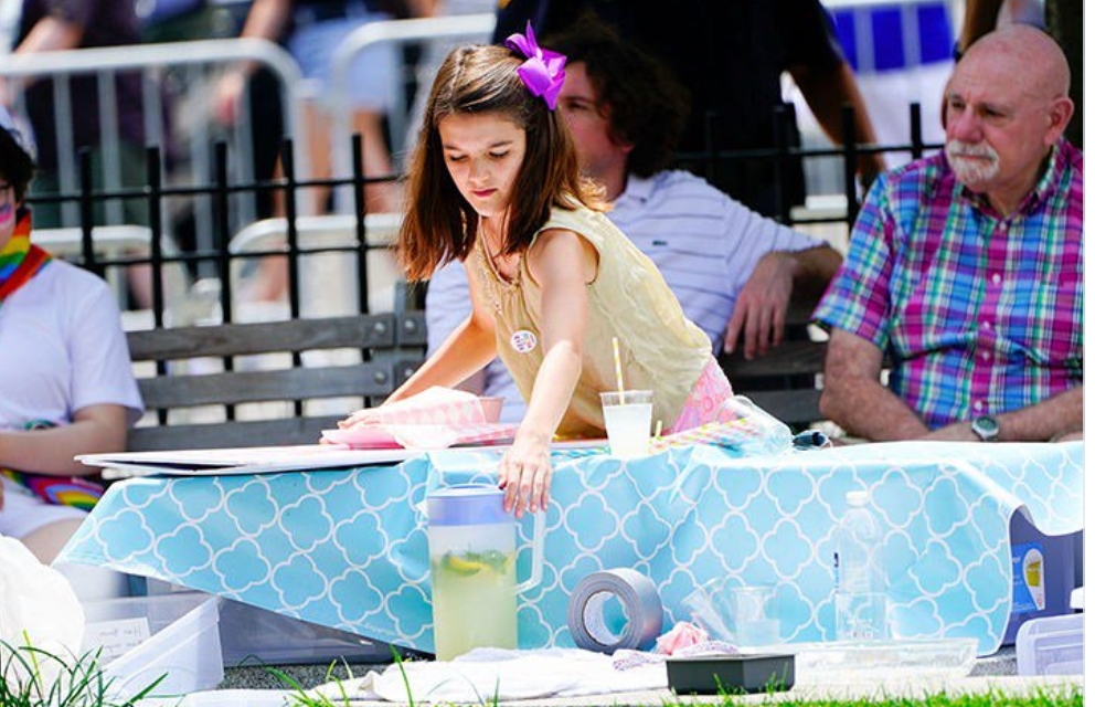 Filha de Tom Cruise e Katie Holmes é flagrada vendendo limonada na parada LGBTQ de Nova York