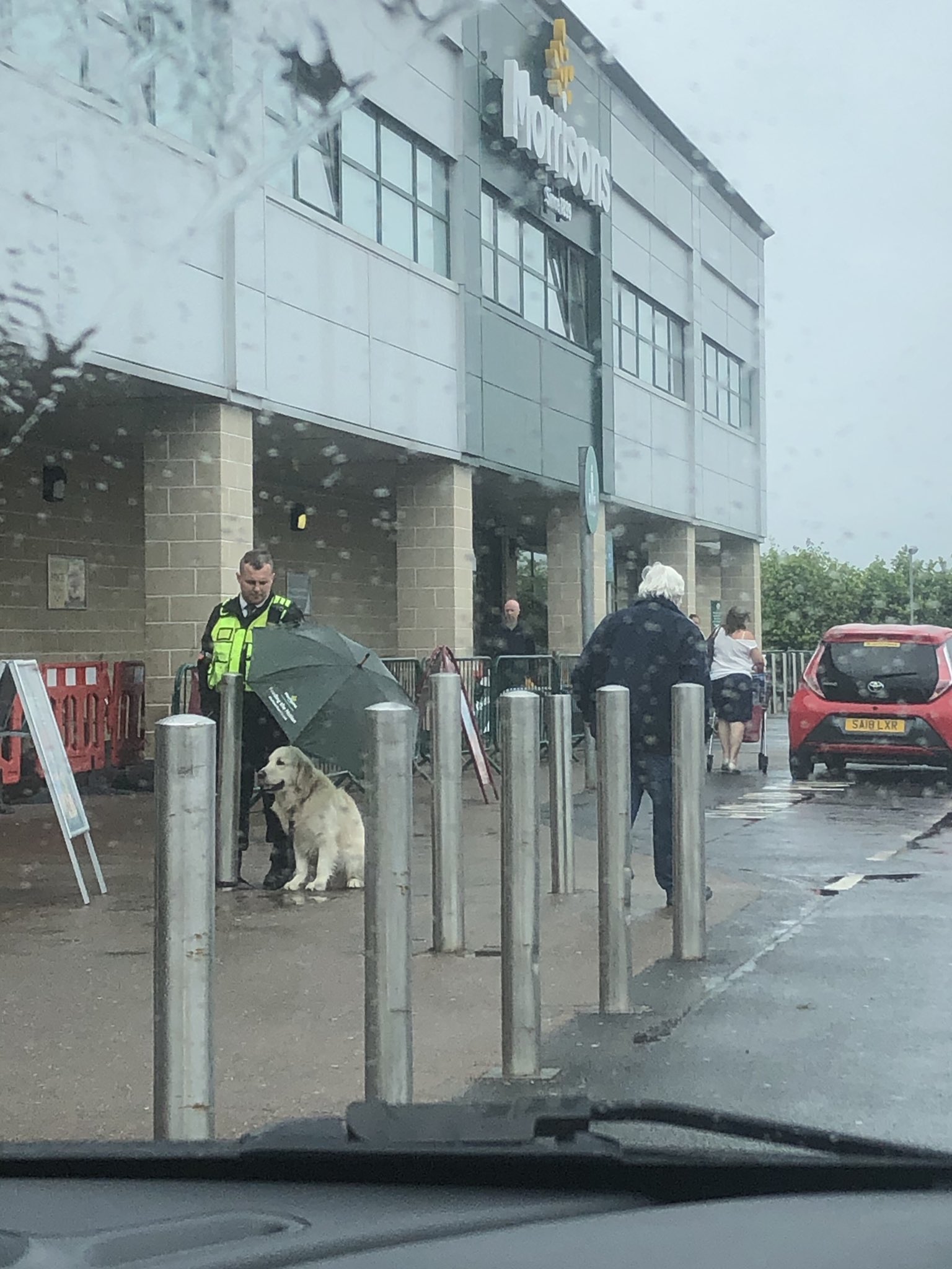 Segurança usa o próprio guarda-chuva para proteger cão à espera do dono